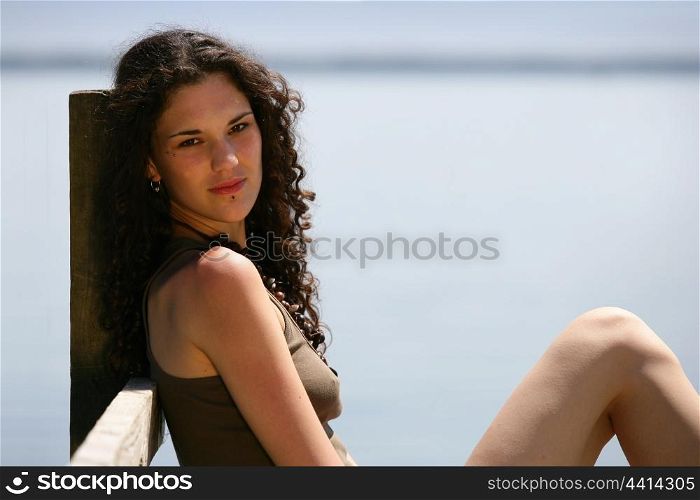 Summery woman sitting on a wooden jetty