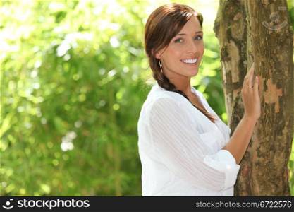 Summery woman standing against a tree