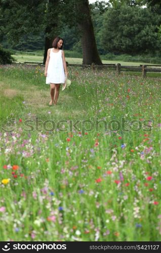 Summery woman walking through a pretty wild flower meadow