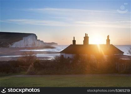 Sun bursts over coastguard cottages at Seaford Head with Seven Sisters cliffs in background