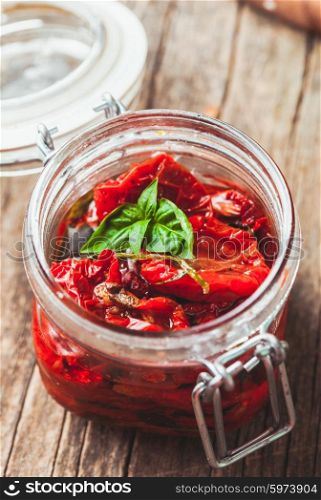 sun dried tomatoes in a glass jar with fresh basil. sun dried tomatoes