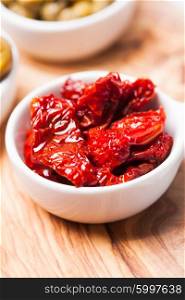 Sun dried tomatoes - in a white saucer on a board. Sun dried tomatoes