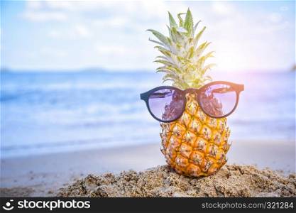 Sun glass is on pineapple at beach sea view background,Summer holiday concept