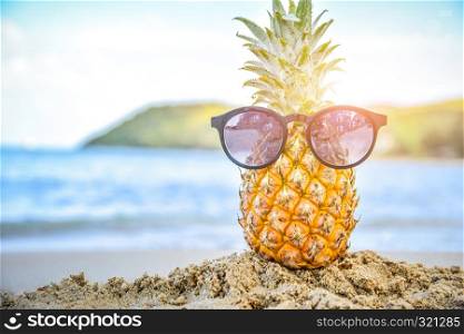 Sun glass is on pineapple at beach sea view background,Summer holiday concept
