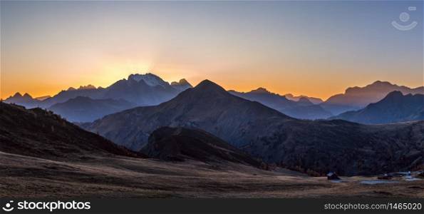 Sun glow and lust sunlight in evening hazy sky. Italian Dolomites mountain panoramic peaceful view from Giau Pass. Climate, environment and travel concept scene.