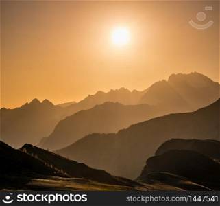 Sun glow in evening hazy sky and mountain silhouettes view. Peaceful view from Giau Pass. Climate, environment and travel concept scene.