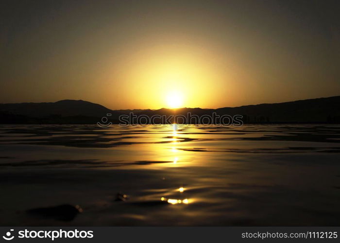 Sun light reflections on water surface. View if a lake at sunset.