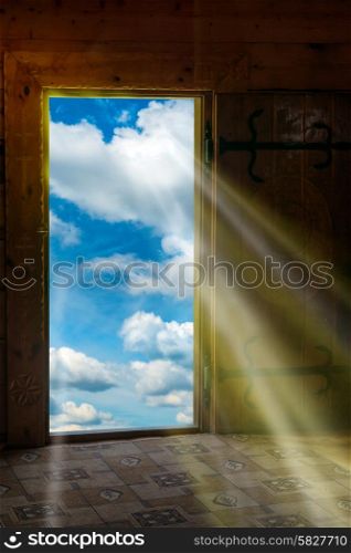 Sun light shining through wooden door from new world with blue sky and clouds