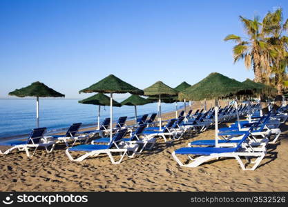 Sun loungers on a beach at the popular resort of Marbella in Spain, Costa del Sol, Andalusia region, Malaga province.