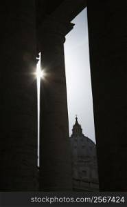Sun peeking through doric columns in Saint Peter&acute;s Square in Vatican City, Italy.