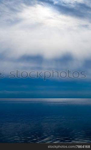Sun rays and bright clouds above dark water.
