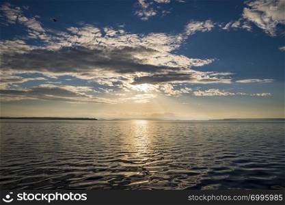 Sun rays beaming through picturesque clouds above the sea. Sun, clouds and water, sea photography.