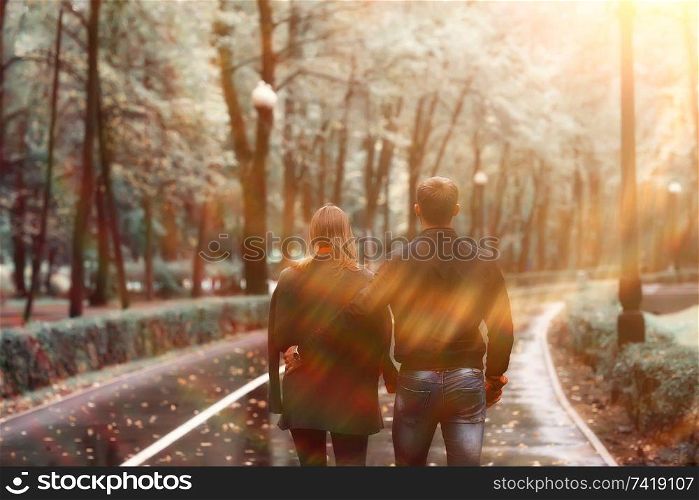 sun rays in the autumn park, a couple in love / young man and woman are walking, autumn view of the sunny park, the rays of the sun, warm autumn background