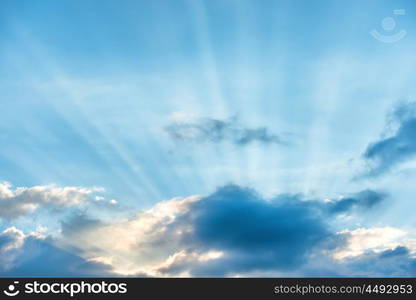 Sun rays shining through cloud on blue sunset sky