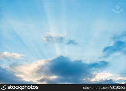 Sun rays shining through cloud on blue sunset sky