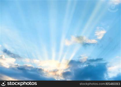 Sun rays shining through cloud on blue sunset sky. Sun rays shining through cloud