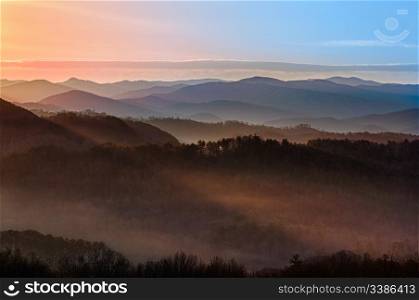Sun rising over snowy mountains of Smokies in early spring with fog in valleys