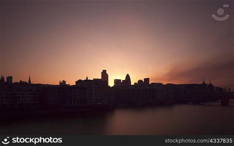 Sun rising over urban buildings on river