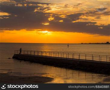 Sun seting on the horizon over pier