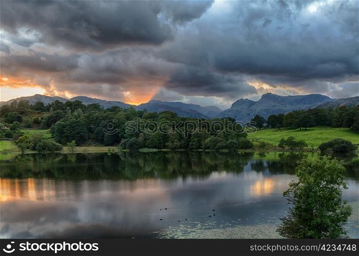 Sun setting over Langdale Pikes with Loughrigg Tarn in foreground