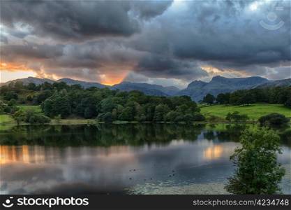 Sun setting over Langdale Pikes with Loughrigg Tarn in foreground