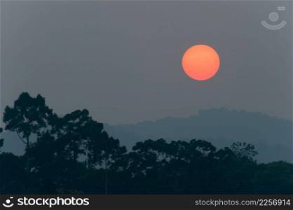 Sun setting over the mountain and tropical forest. Full sun. Massive dark spot on sun. Silhouette. Background, Texture. Summer season Khao Yai National Park. World Heritage Site. Thailand.
