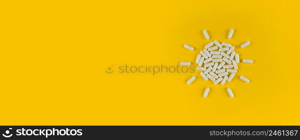 Sun shape made from white pills capsules on a yellow backdrop with copy space.. Sun shape made from white pills capsules on yellow backdrop with copy space.