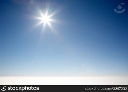 Sun shining in a clear blue sky over a sea of clouds; italian alps.