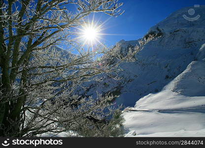Sun shining onto snow covered mountain