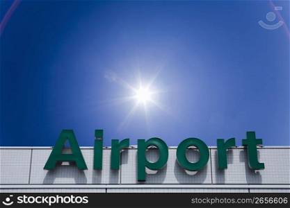 sun shining over airport sign