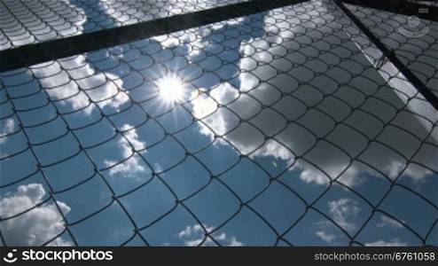 Sun shining through the chain link iron wire fencing