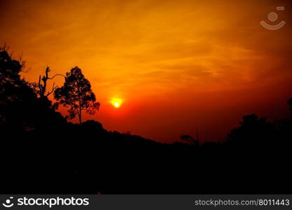 Sun shining through the clouds with silhouetted mountians