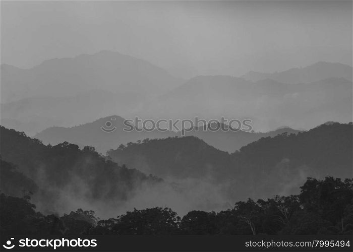 Sun shining through the clouds with silhouetted mountians, black and white tone
