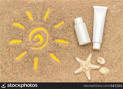 Sun sign drawn on sand, starfish and white tube, bottle of sunscreen. Template mockup for your design. Creative top view.. Sun sign drawn on sand, starfish and white tube, bottle of sunscreen. Template mockup for your design. Creative top view