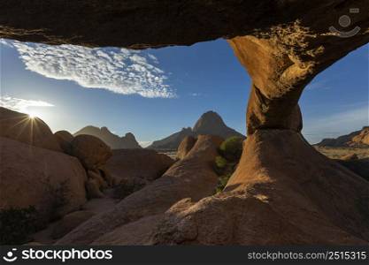 Sun starburst over red granite rocks Spitzkoppe Namibia
