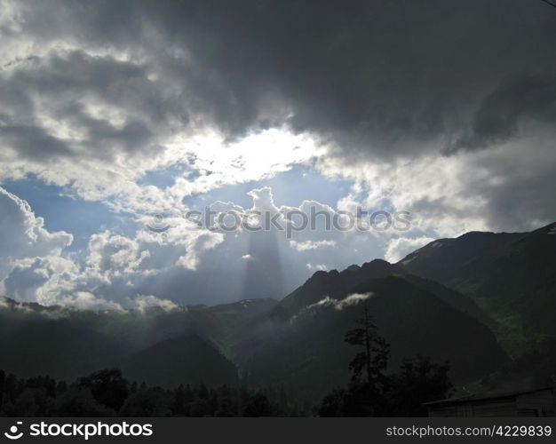 Sun strikes from clouds to the mountain