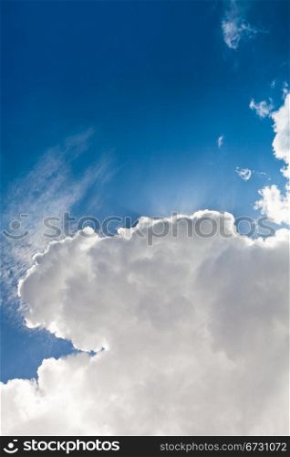 sun under big cumulus cloud in blue summer sky