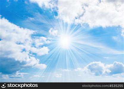 Sun with rays on blue sky with white clouds