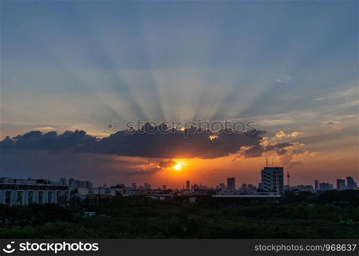 Sunbeam through the dramatic cloud during sunset time, with silhueete building in background