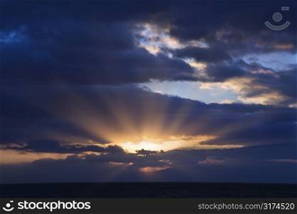 Sunbeams coming through clouds at sunrise over Maui, Hawaii, USA.