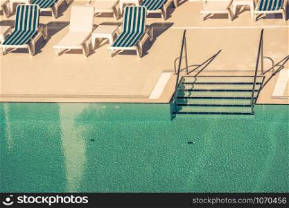Sunbeds and umbrellas with ladder of a swimming pool on a sunny day