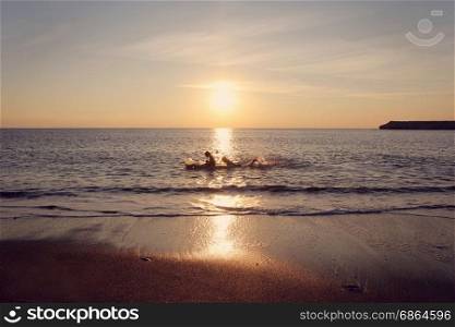 Sundown and sea tide. Dramatic sundown on a sea and kids silhouettes on a boat