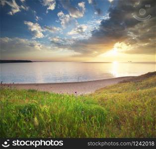 Sundown seascape composition. Sky, sea, and green grass.