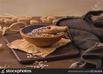 Sunflower seeds in a ceramic bowl on a rustic kitchen countertop.