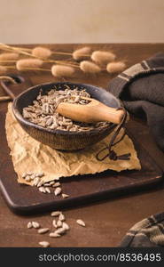 Sunflower seeds in a ceramic bowl on a rustic kitchen countertop.