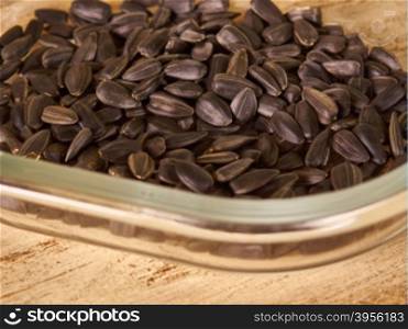 sunflower seeds in transparent Cup on wooden background. scattering of seeds