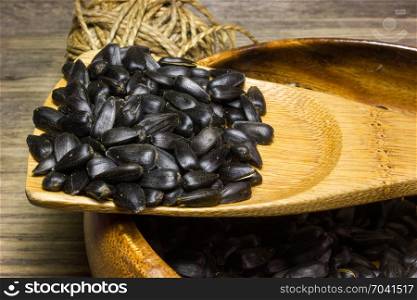 Sunflower seeds in wooden plate on wooden background.