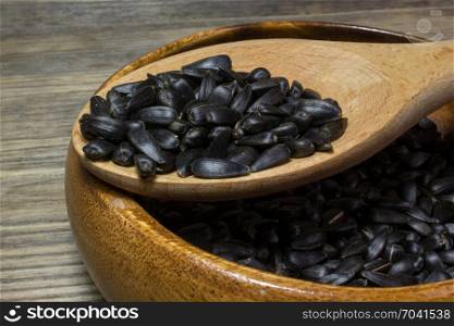 Sunflower seeds in wooden plate on wooden background.