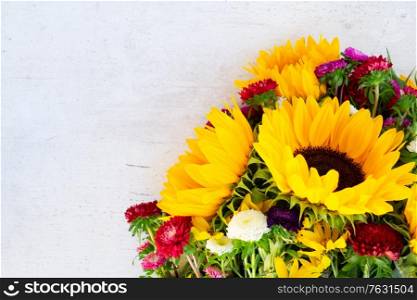 Sunflowers and aster fresh blooming flowers, top view on white wooden table background with copy space. Sunflowers on white