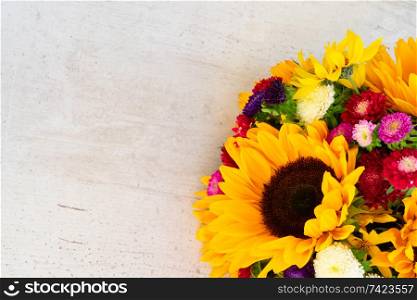 Sunflowers and aster fresh flowers on white wooden table background with copy space. Sunflowers on white